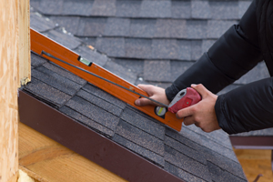 Roofer holding a tape measure and level - Legit Exteriors, serving Portland OR & Vancouver WA explains how to determine the pitch of your roof. 